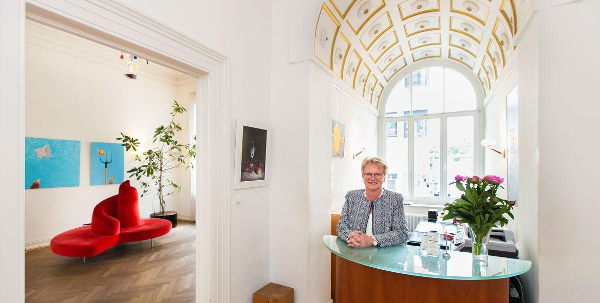 Eine Frau sitzt an einem Schreibtisch mit einer Vase mit Blumen vor ihr