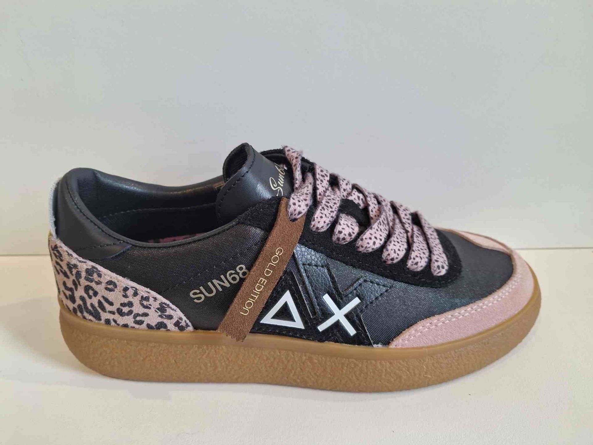 Zapatilla negra con detalles rosas y estampado de leopardo, suela y cordones marrones.