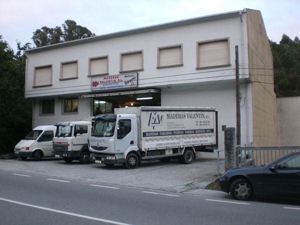Una fila de camiones están estacionados frente a un edificio con las letras ls en el costado