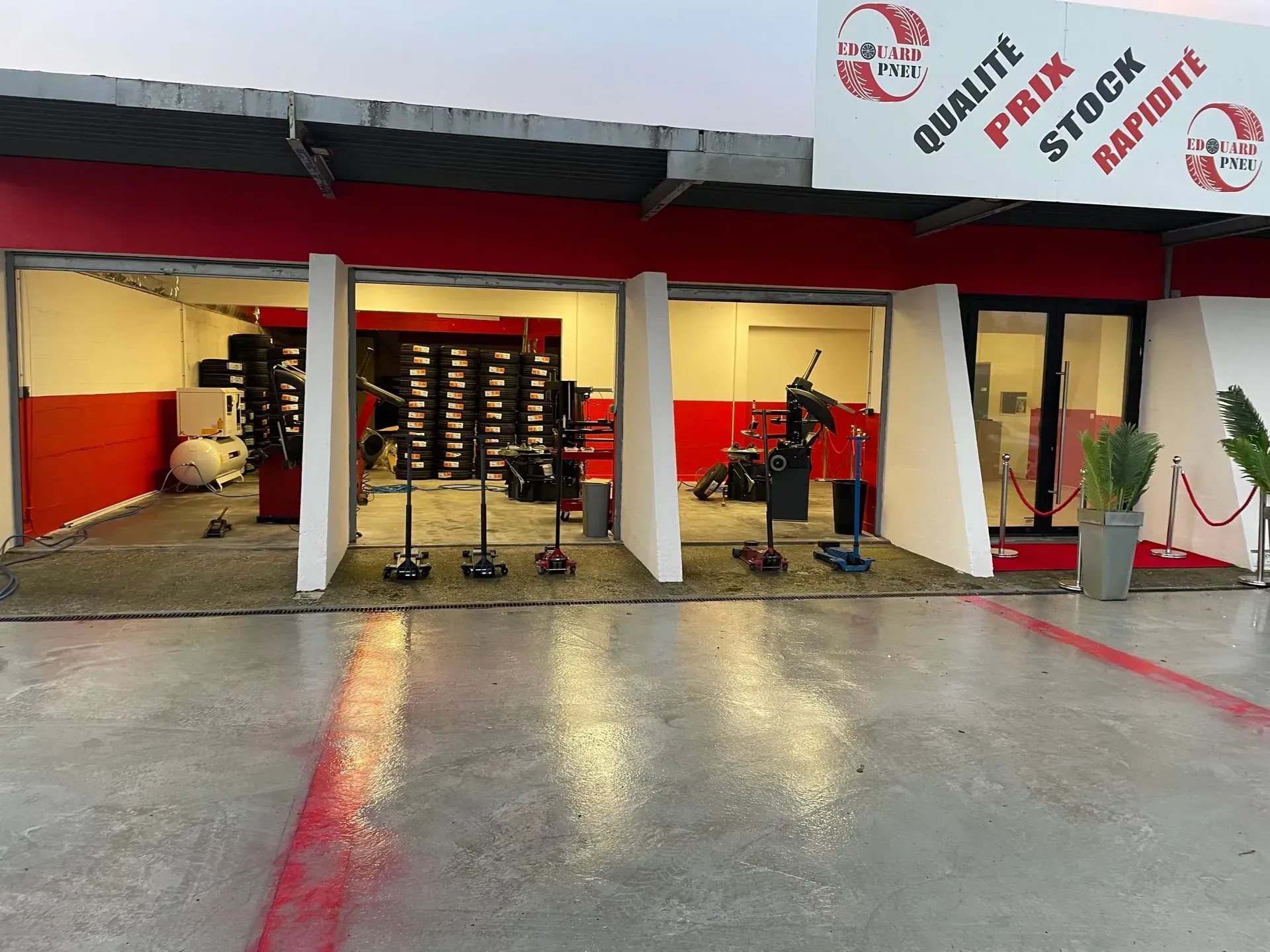 Extérieur d'un garage auto rouge et blanc avec des rayons ouverts.