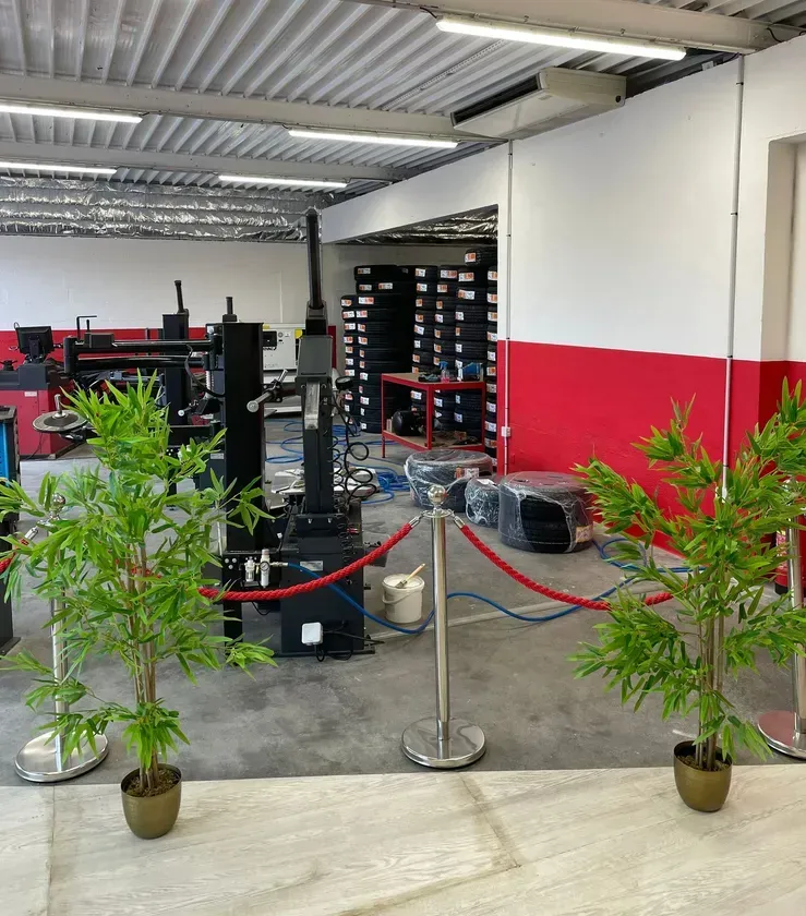 Un espace de travail industriel avec des machines, des murs rouges et blancs et des plantes de bambou.