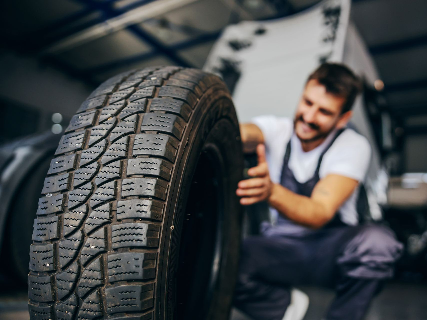 Un mécanicien tient un pneu dans un garage.