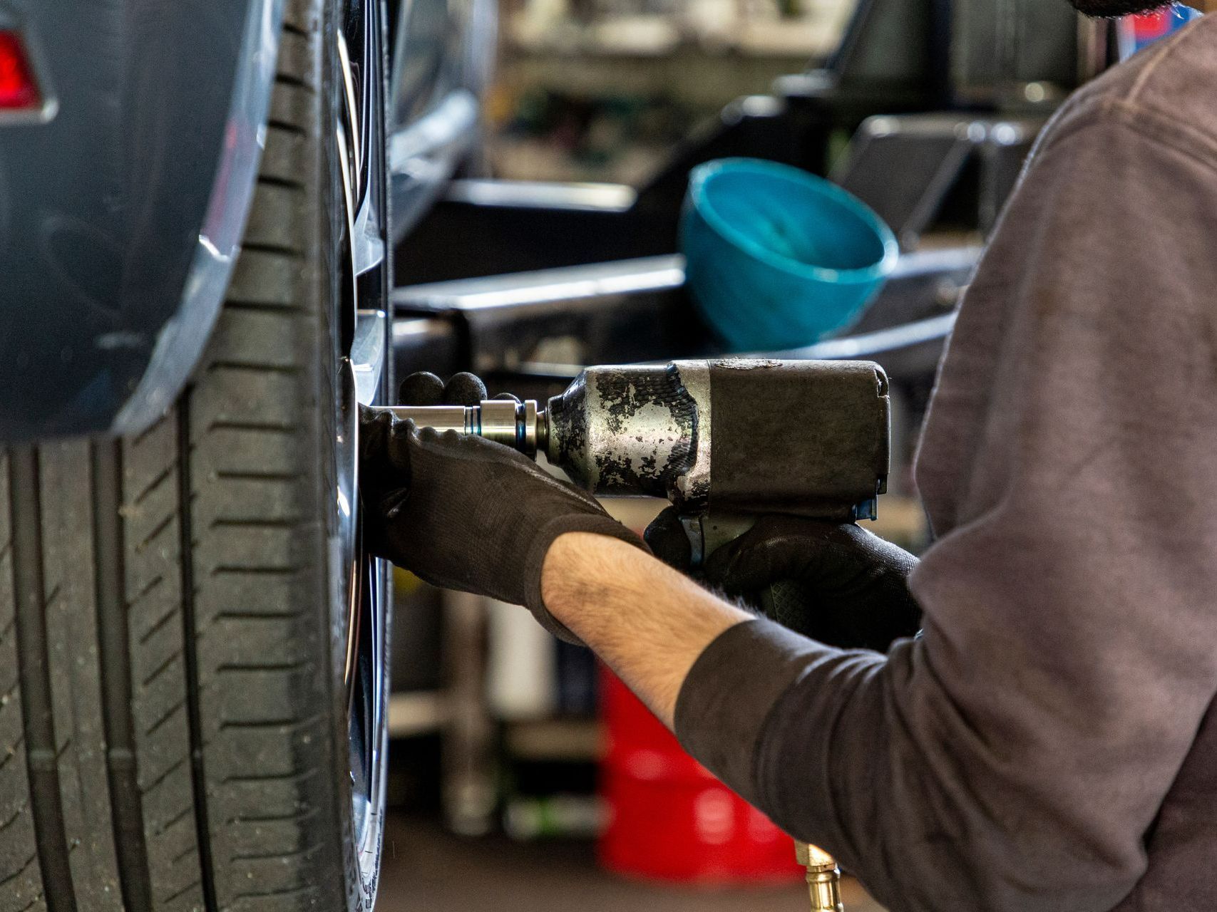 Un mécanicien utilise une clé à chocs pour serrer les écrous de roue d'un pneu de voiture dans un atelier.