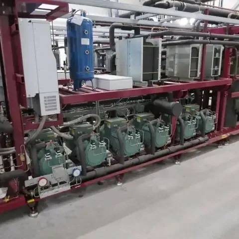 Unidad de refrigeración industrial con múltiples compresores y tuberías, sobre un fondo industrial gris claro.