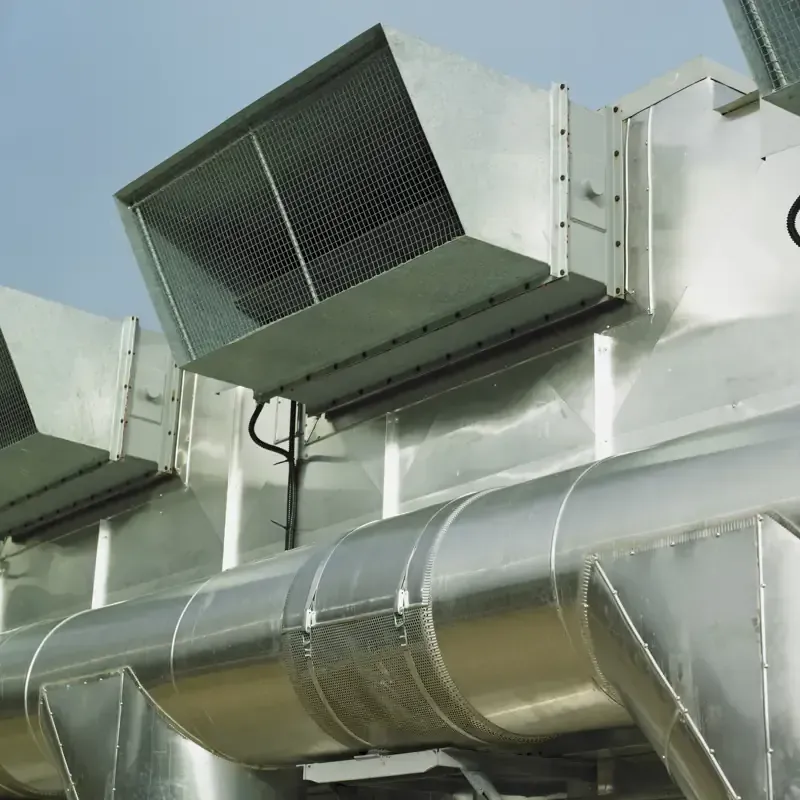 Conductos metálicos de aire acondicionado con rejillas y aislamiento, en exterior.