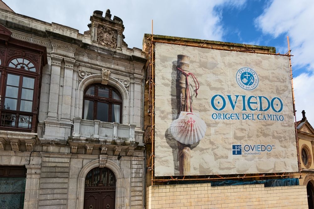 Fachada de un edificio de piedra con una gran pancarta publicitaria de