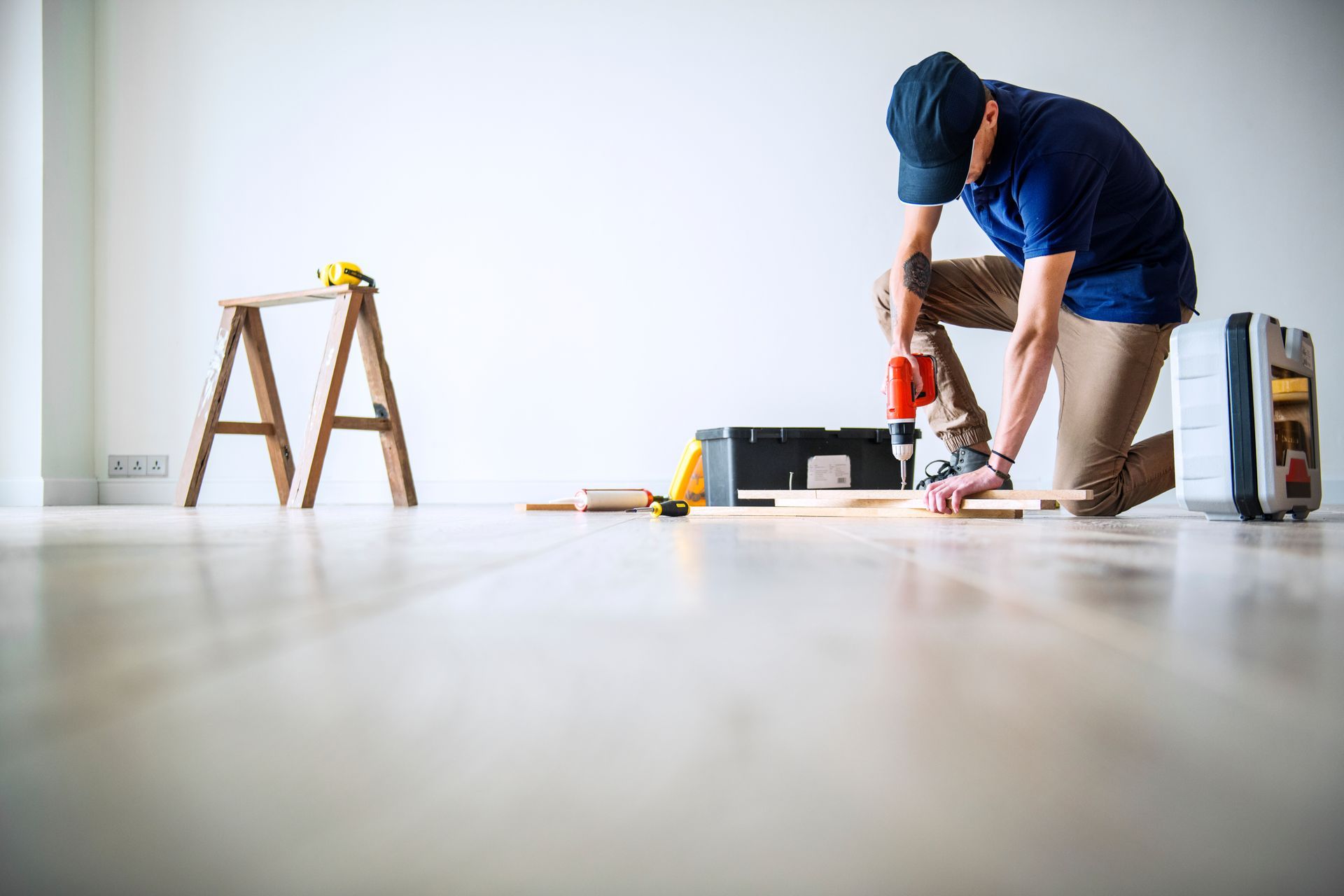 Ein Mann kniet auf dem Boden und bearbeitet ein Stück Holz. Service-Engel.ch GmbH