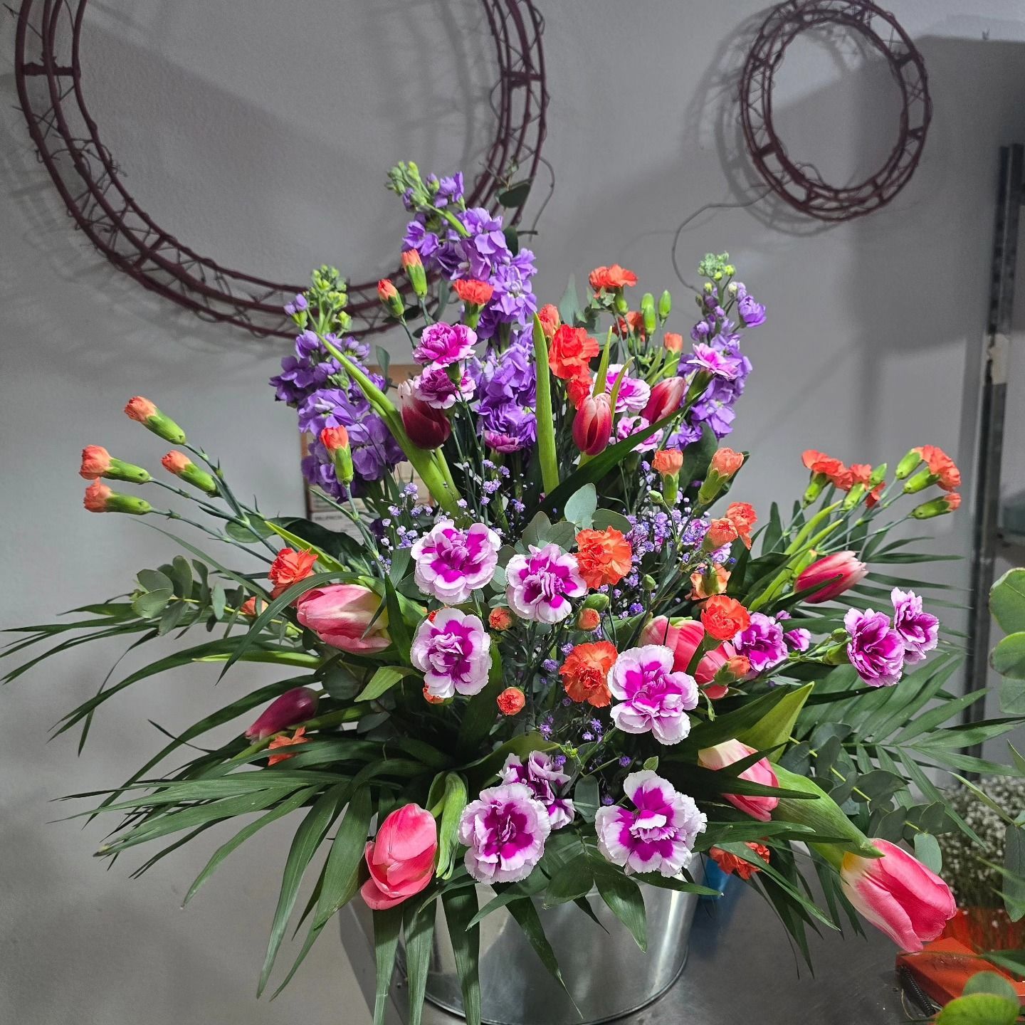 Un ramo de flores en un cubo de metal sobre una mesa.