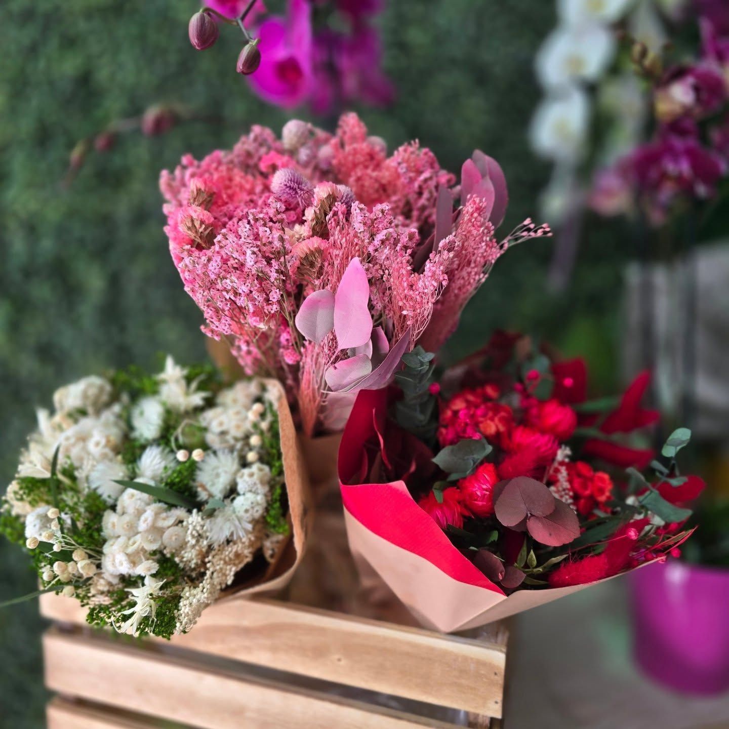 Tres ramos de flores están en una caja de madera.