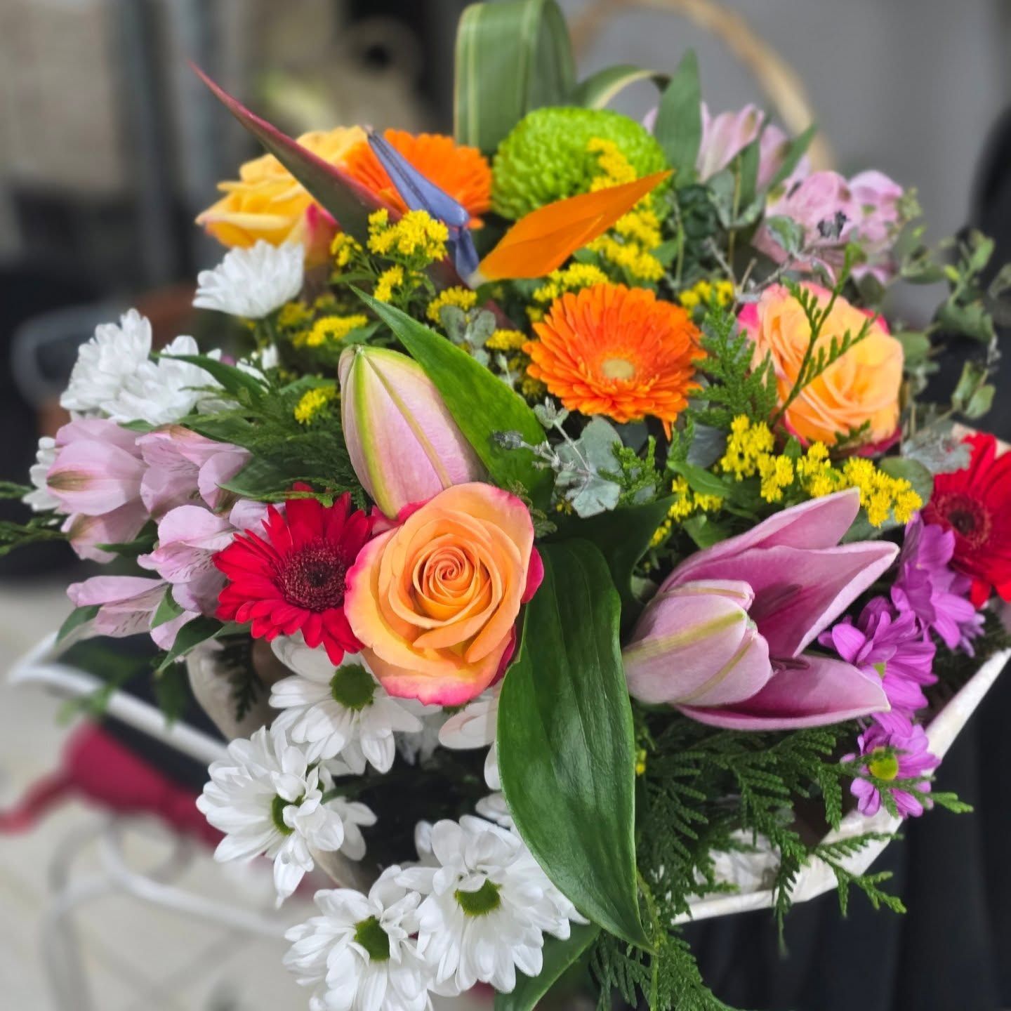 Un ramo de flores que incluye rosas y margaritas.