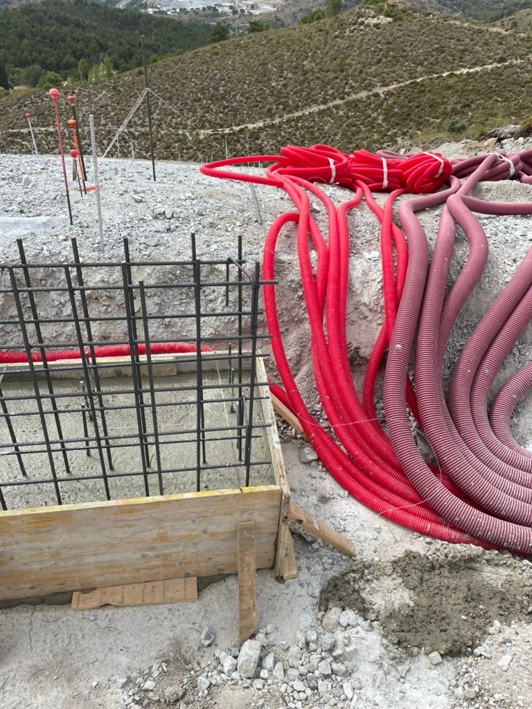 Sitio de construcción: Conductos eléctricos rojos emergen de una estructura de concreto y varillas de refuerzo