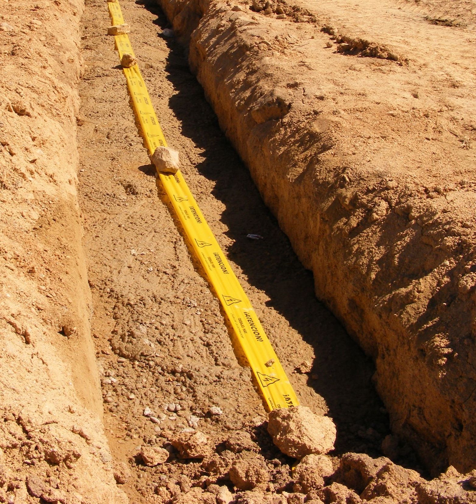 Regla de nivel amarilla en una zanja, que garantiza una profundidad uniforme para la construcción en un entorno de tierra.