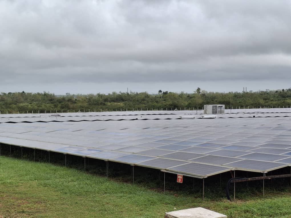 Paneles solares en un campo bajo un cielo nublado.