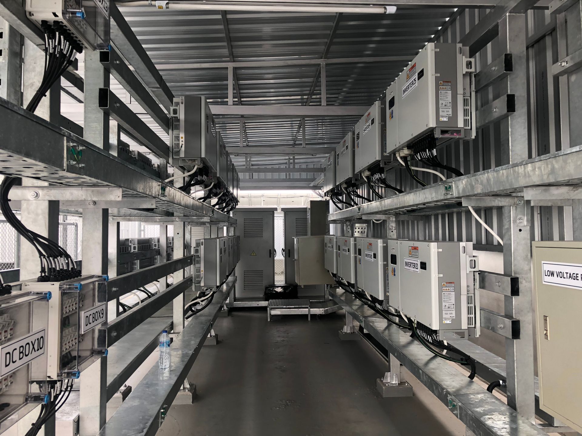 Vista interior de una habitación con estructura de metal con filas de equipos eléctricos y cableado.