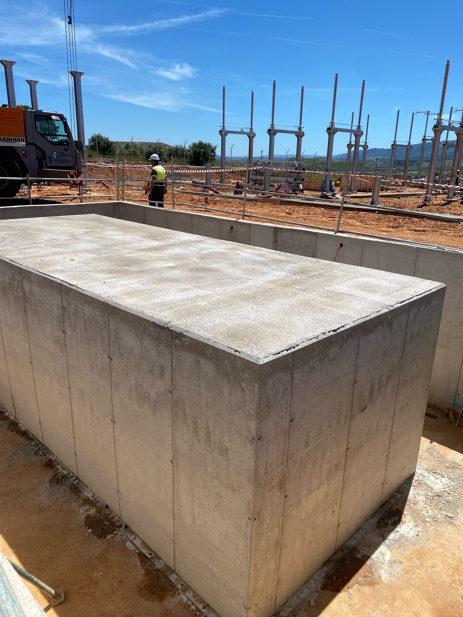 Sitio de construcción de hormigón, trabajador con equipo de alta visibilidad y maquinaria