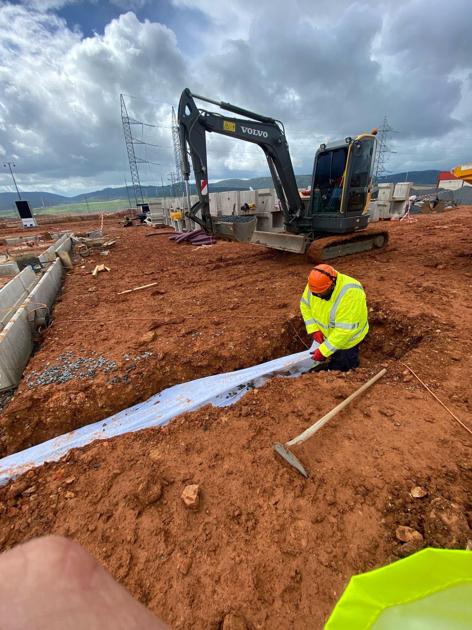 Trabajador de la construcción con chaleco amarillo instalando una franja de drenaje blanca en un sitio de construcción