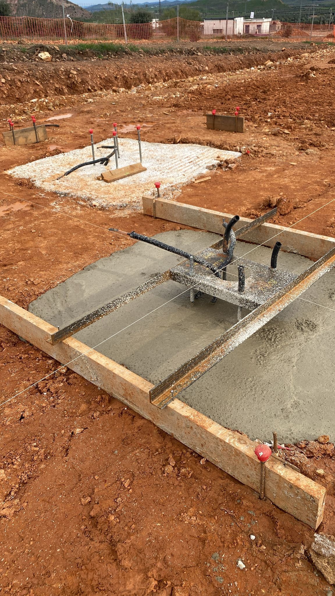Cimentación de hormigón vertida con encofrado de madera en un terreno de tierra.