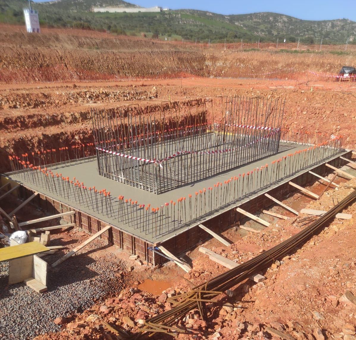 Obra de construcción con cimentación de hormigón y estructura de armadura.