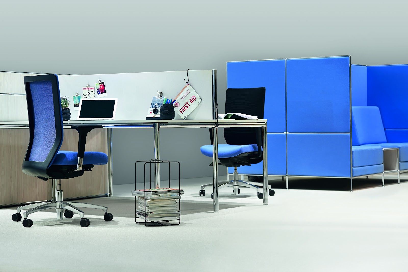 Ein leerer schwarzer Bürostuhl neben einem Schreibtisch in einem modernen Arbeitsbereich mit weißer Backsteinwand und Pflanze.