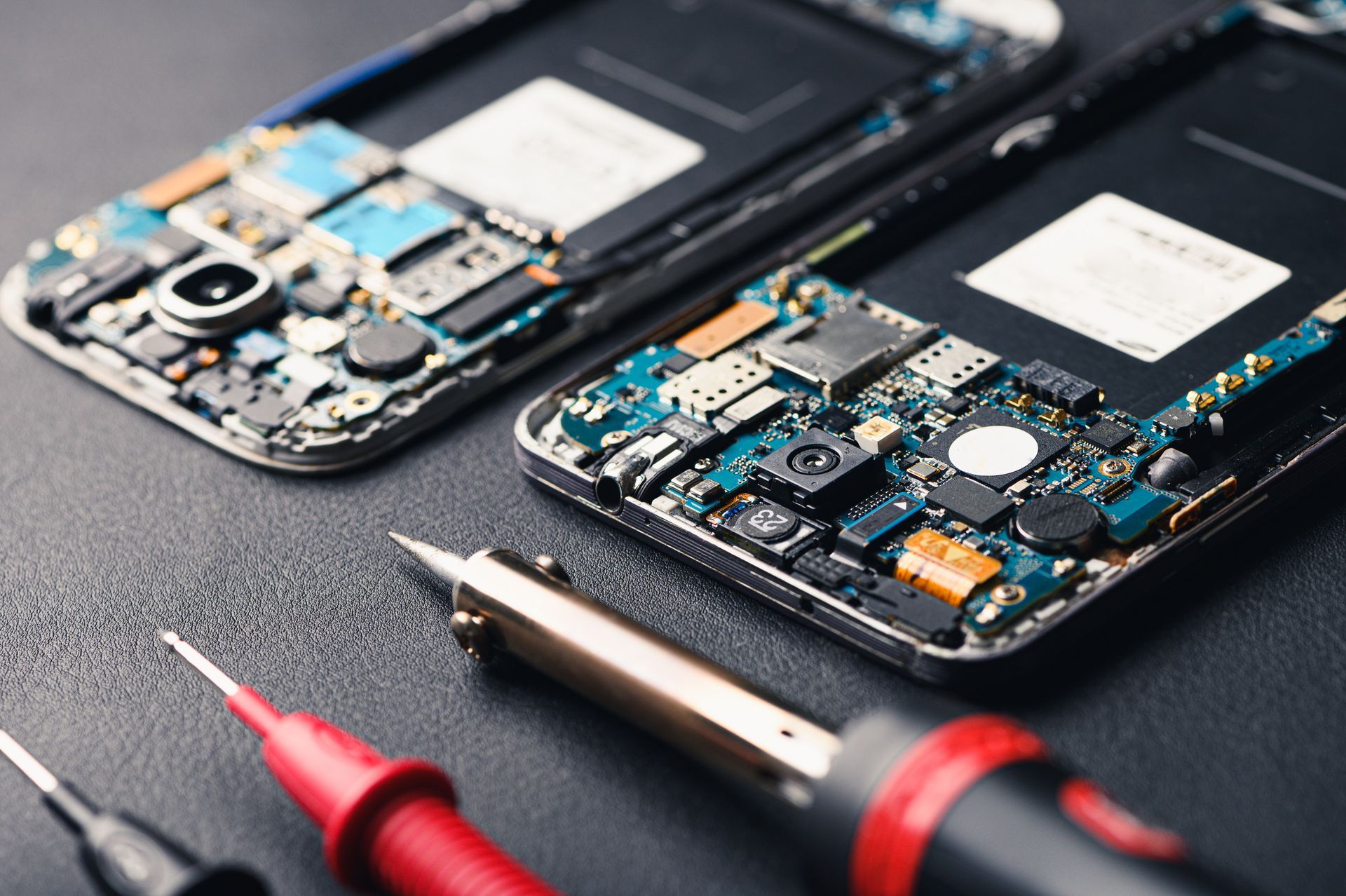Se están reparando dos teléfonos celulares con herramientas sobre una mesa.