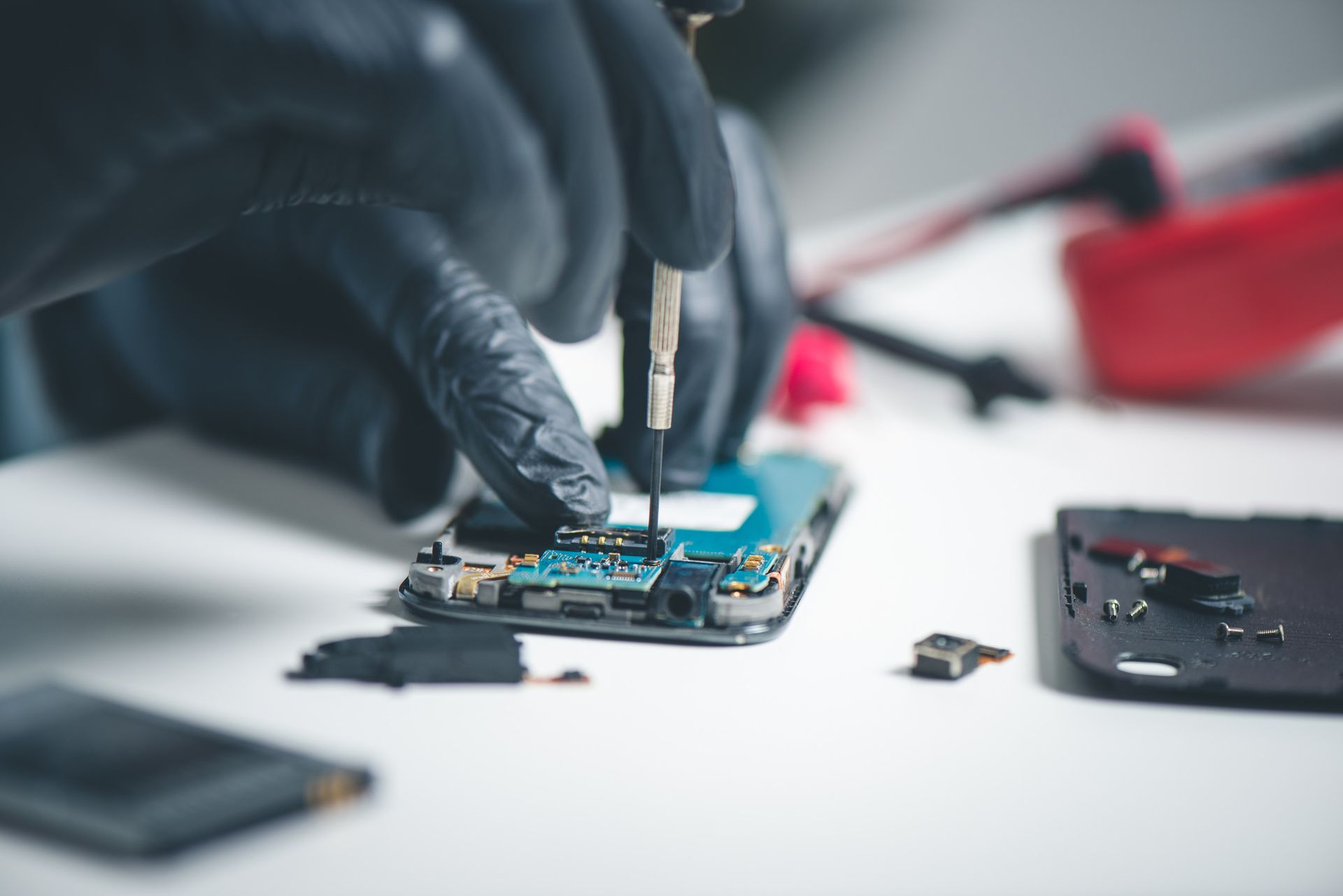 Una persona está reparando un teléfono celular con un destornillador.