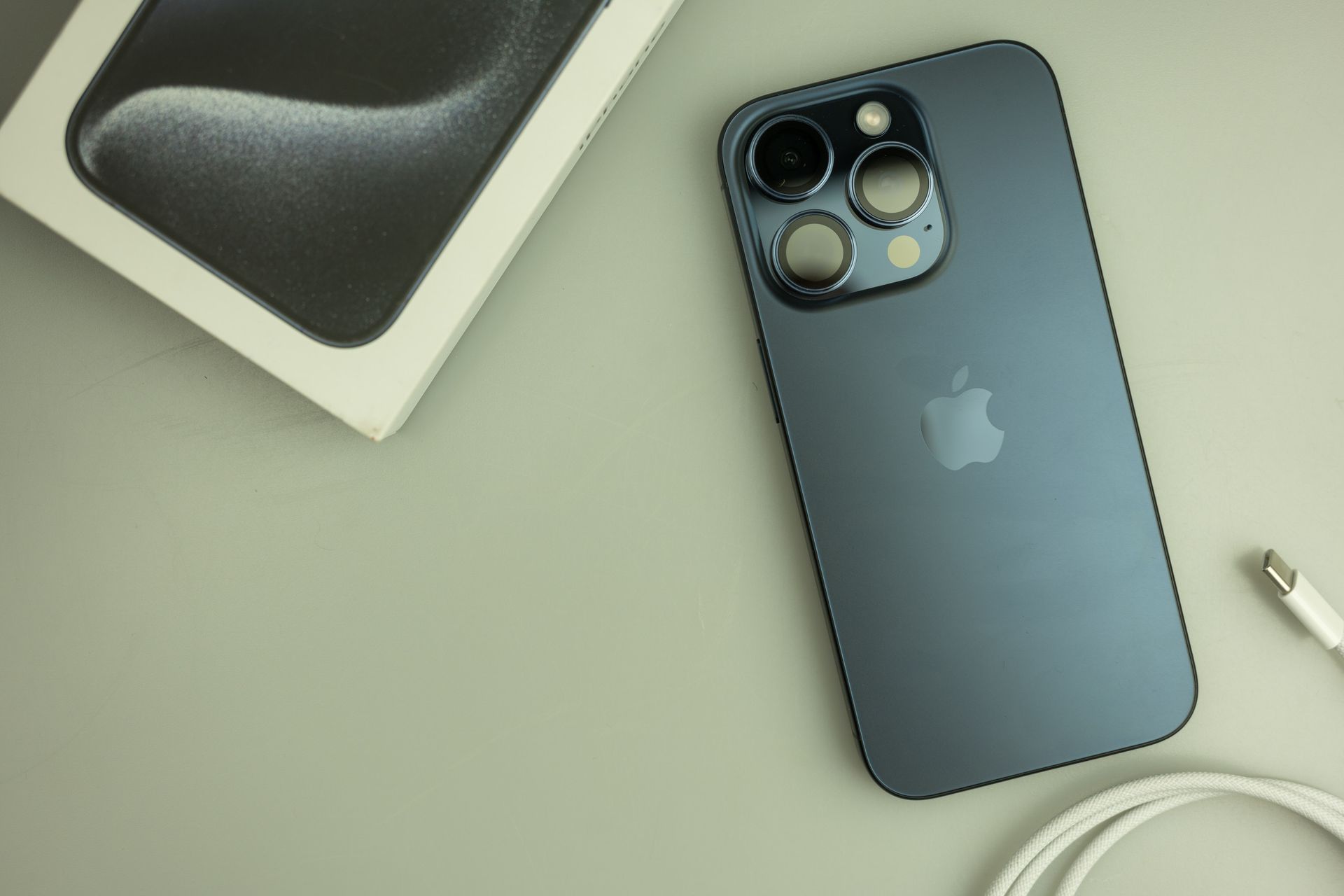 Un iPhone 13 Pro azul está sobre una mesa junto a su caja.