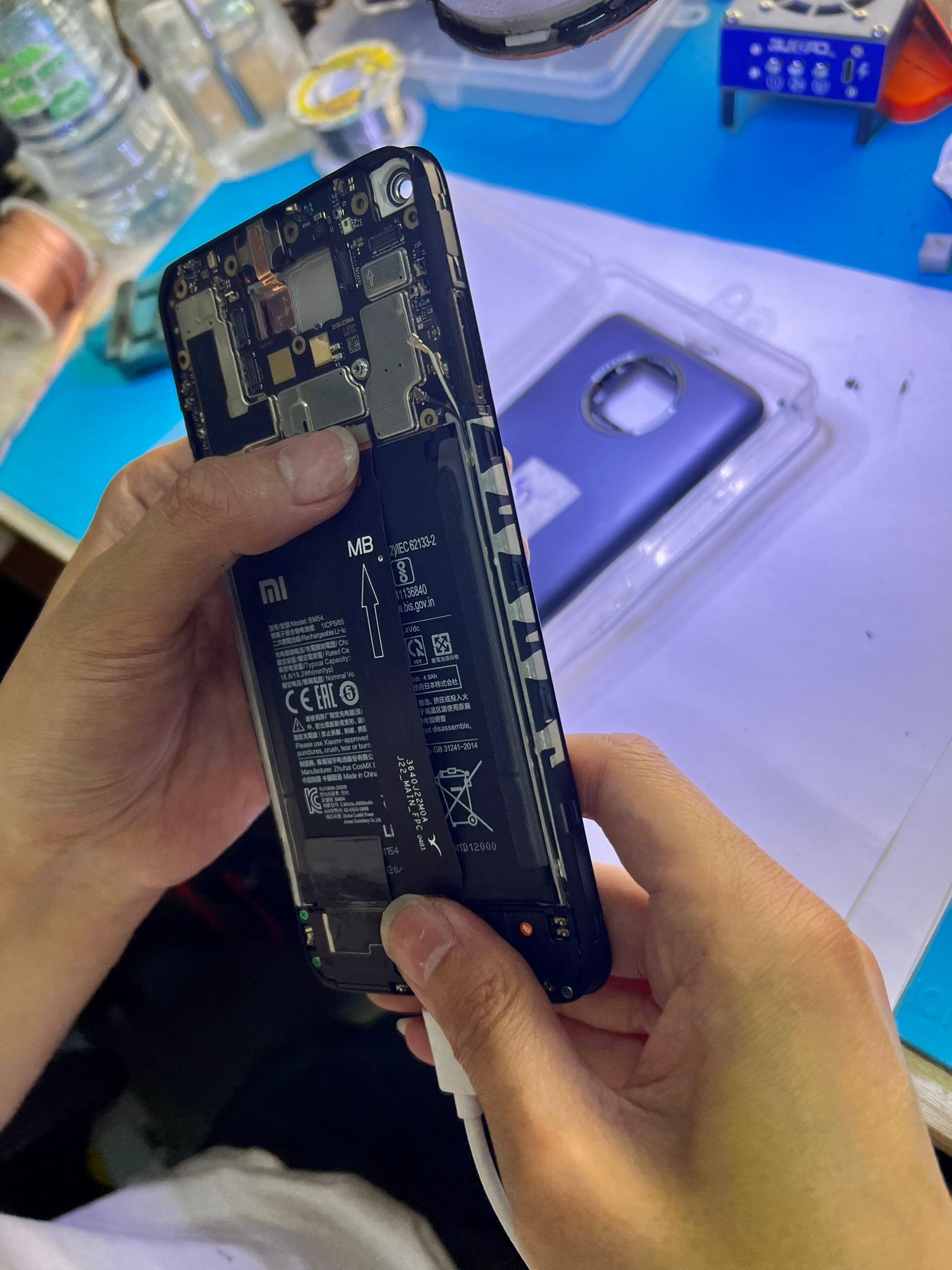 Una persona está reparando un teléfono celular con un destornillador.