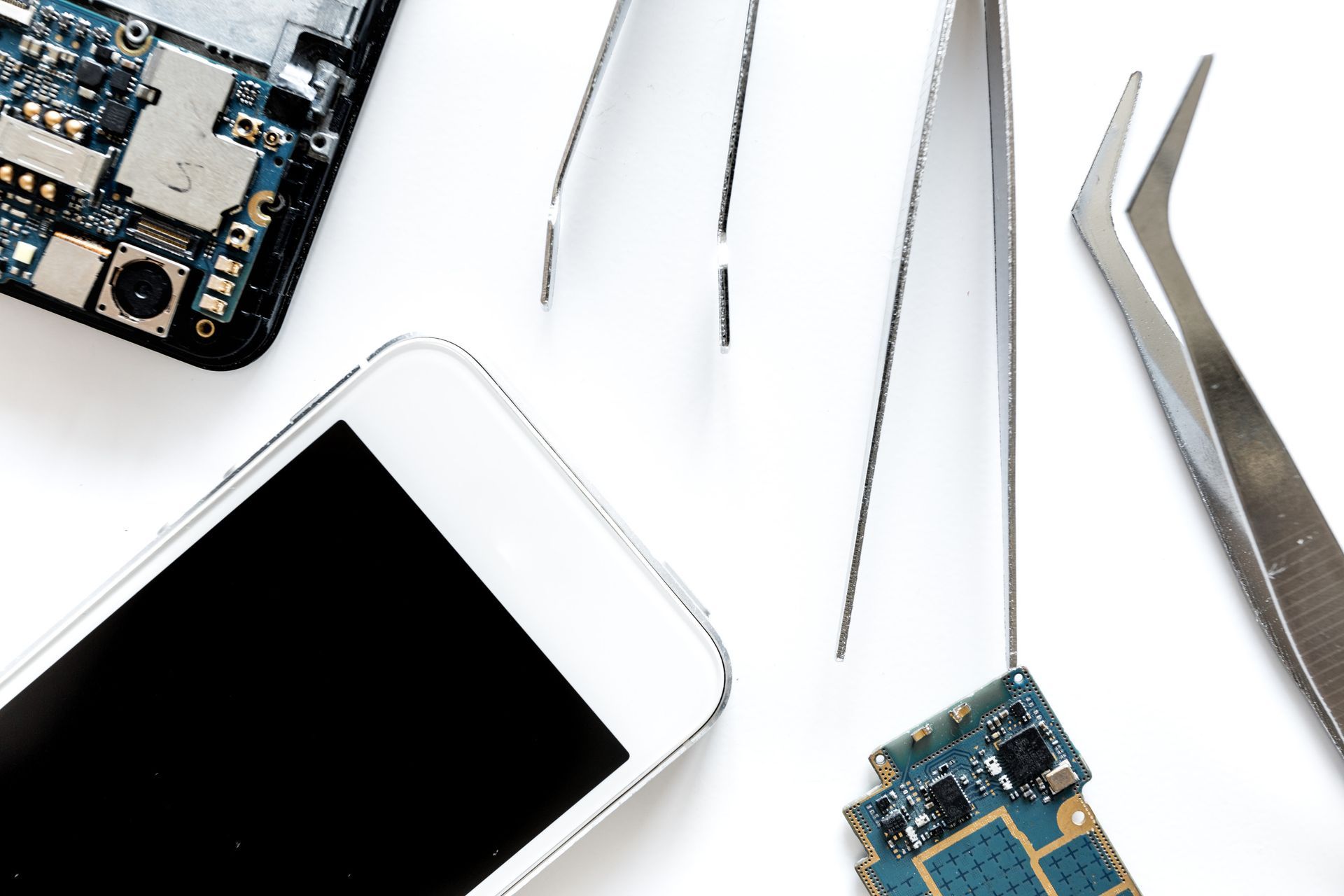 Se está reparando un teléfono celular con pinzas y tijeras.