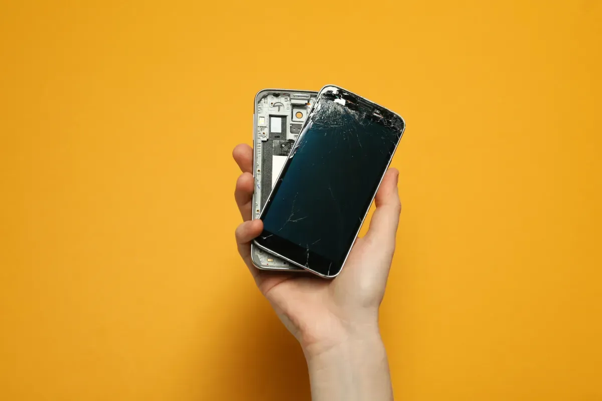 Una persona sostiene un teléfono celular roto en su mano.