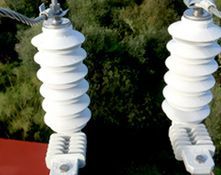 Un primer plano de dos aislantes eléctricos blancos en una línea eléctrica.