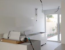 Una cocina con gabinetes blancos y un trapeador verde.