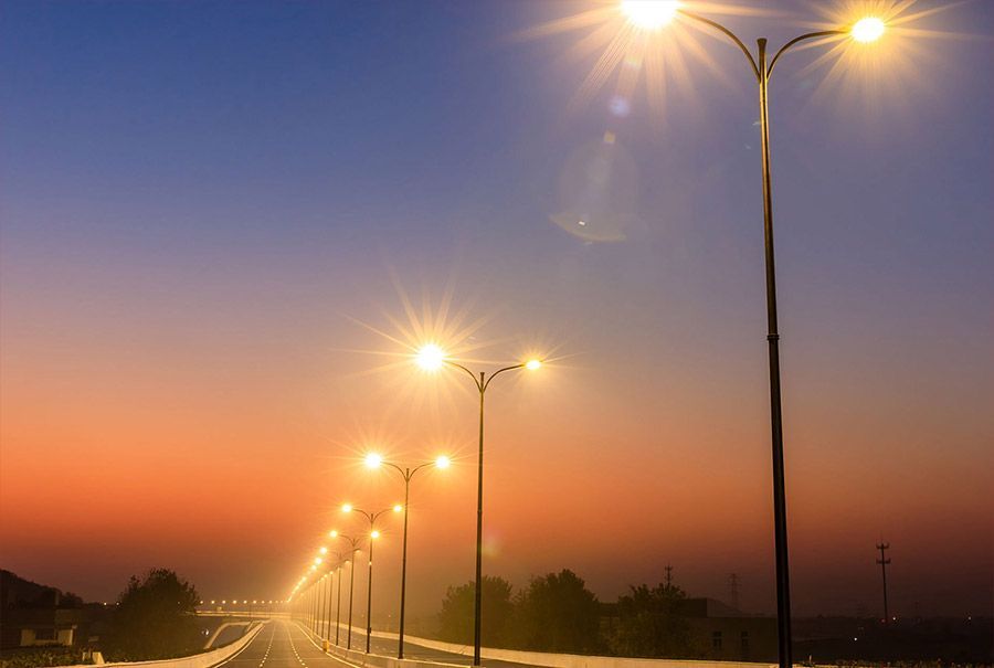 Una hilera de luces de la calle en una carretera al atardecer.