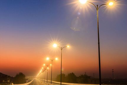 Una hilera de luces de la calle en una carretera al atardecer.
