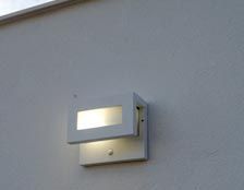 Una luz de pared blanca está en el costado de un edificio.
