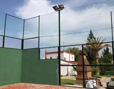 Una cancha de tenis con una pared verde y una valla negra.