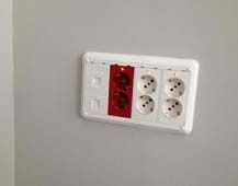 Un tomacorriente eléctrico blanco y rojo en una pared.
