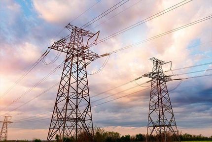 Un par de líneas eléctricas que atraviesan un campo al atardecer.