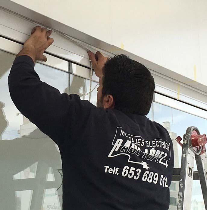 Un hombre está trabajando en una ventana con un número de teléfono en su espalda.