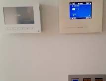 Una pared blanca con un termostato y un monitor encima.