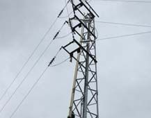 Un poste telefónico con muchos cables contra un cielo nublado.