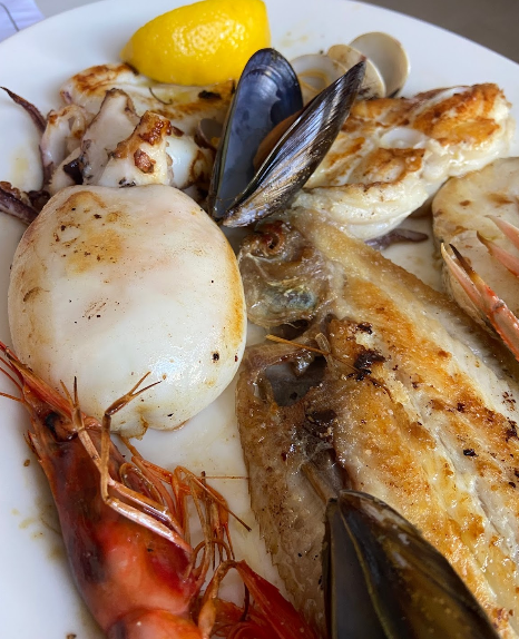 Un plato blanco cubierto con mariscos y una rodaja de limón.