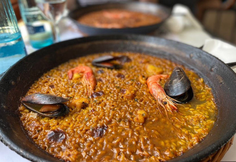 Una sartén de arroz con camarones y mejillones en una mesa.