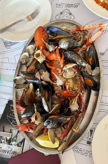 Un plato de mariscos está sobre una mesa con platos y un tenedor.