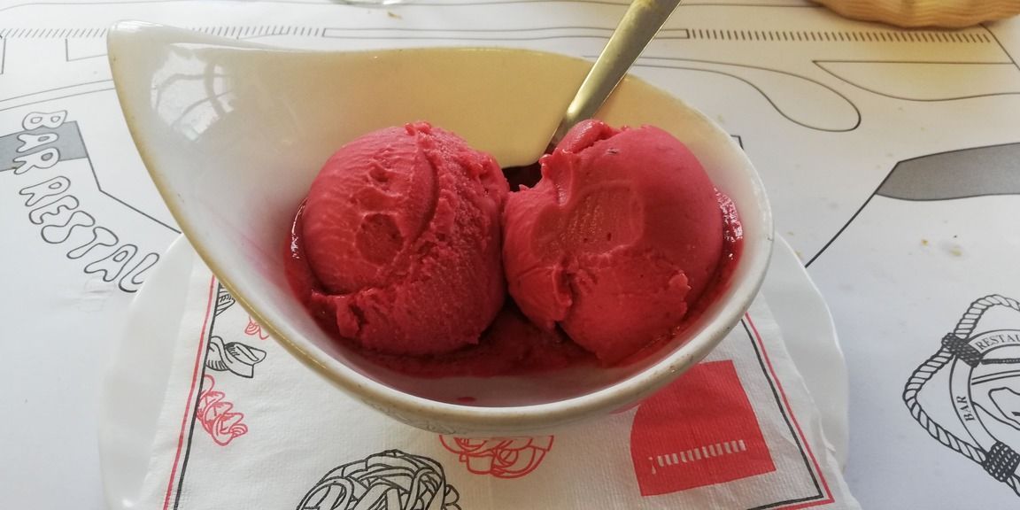 Un tazón de helado rojo con una cuchara dentro.