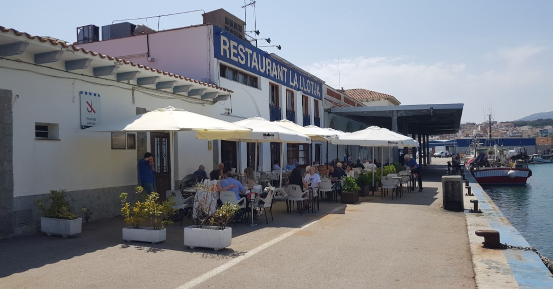 Un grupo de personas están sentadas en mesas afuera de un restaurante.