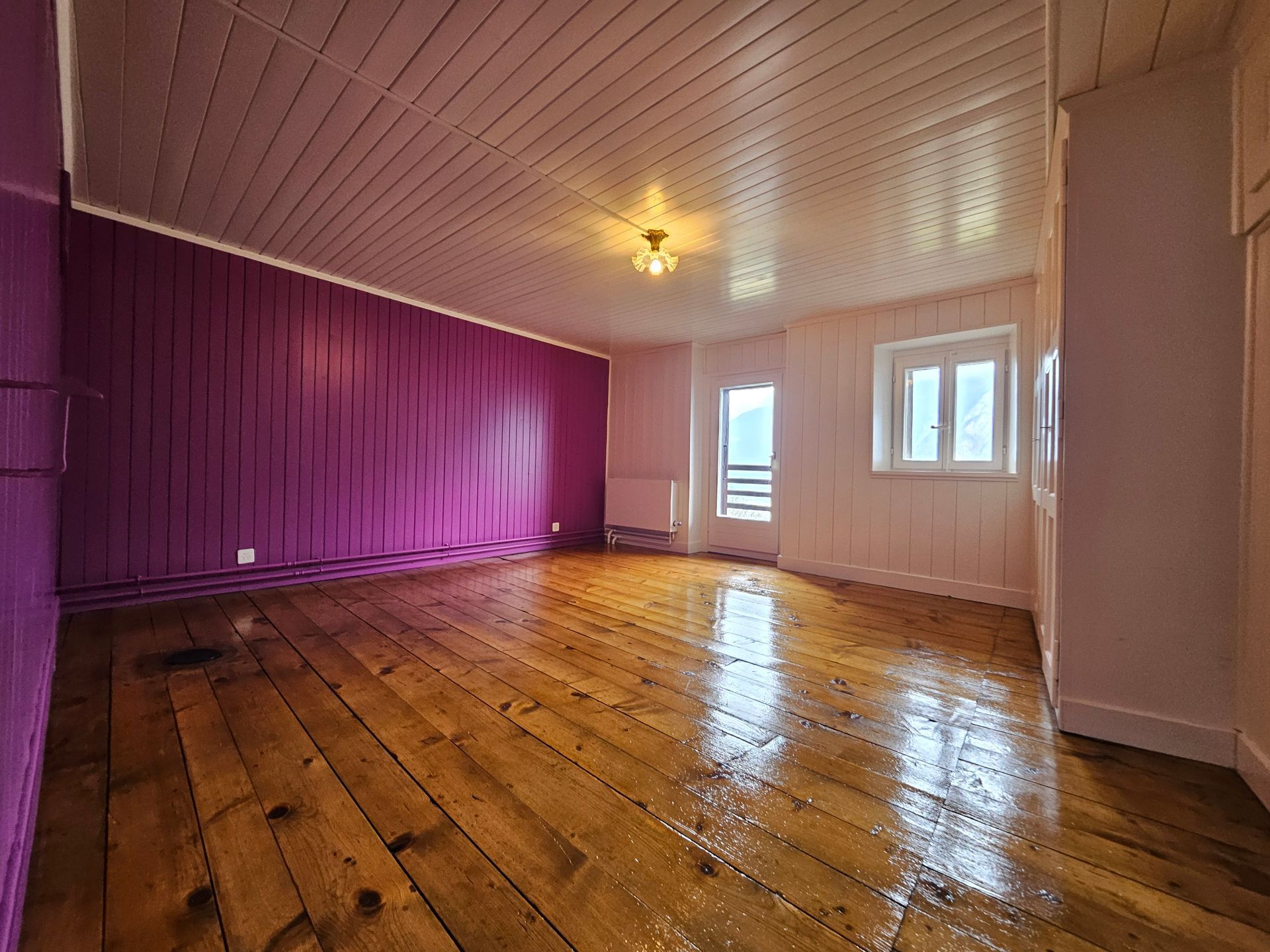 En haut : Intérieur d’une maison mobile avec lambris marron, canapé et table. 