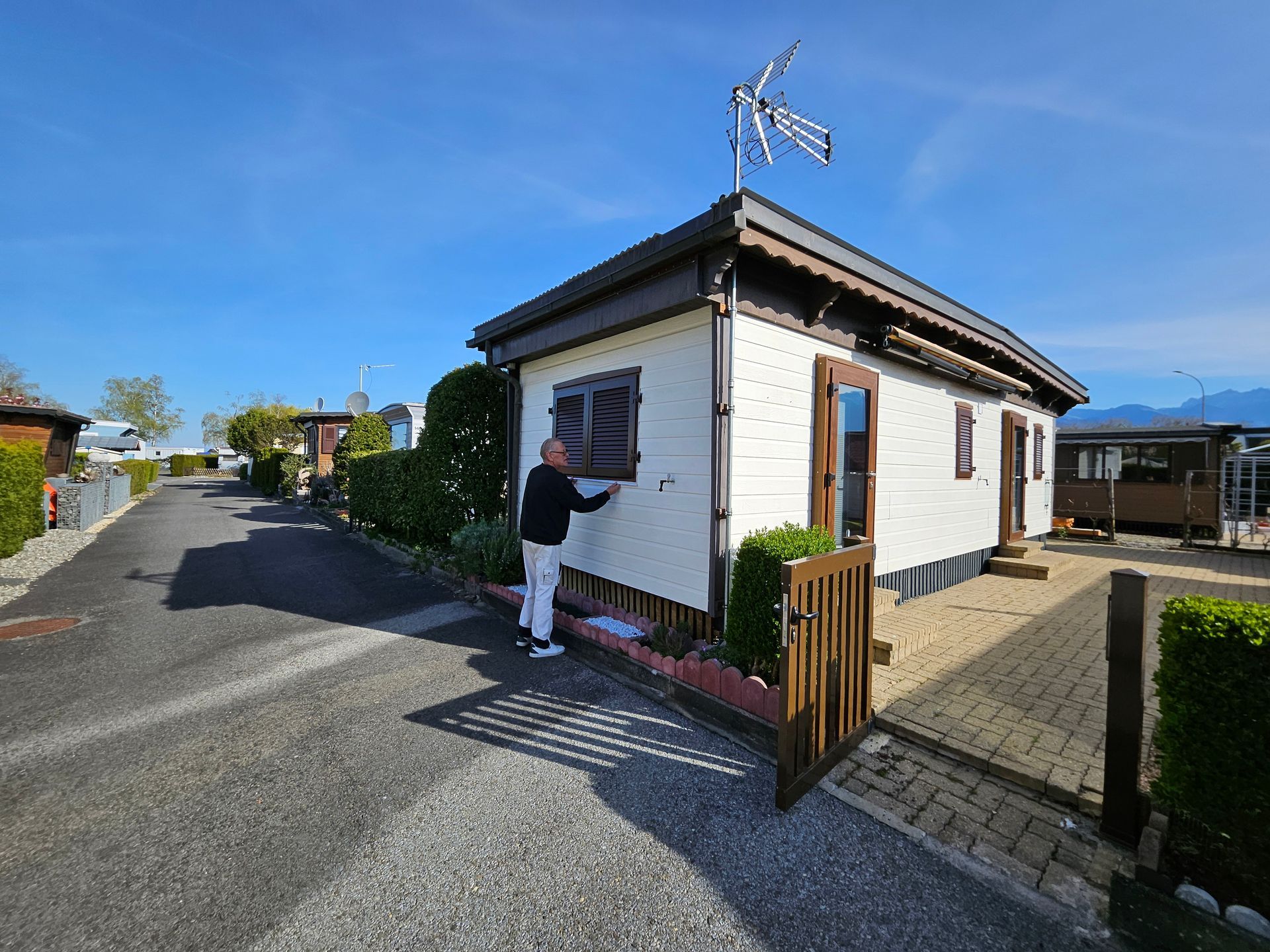 Trois vues d'une chambre : miroir en pied, table de chevet et lit contre un mur à motifs magenta. Sol en bois.