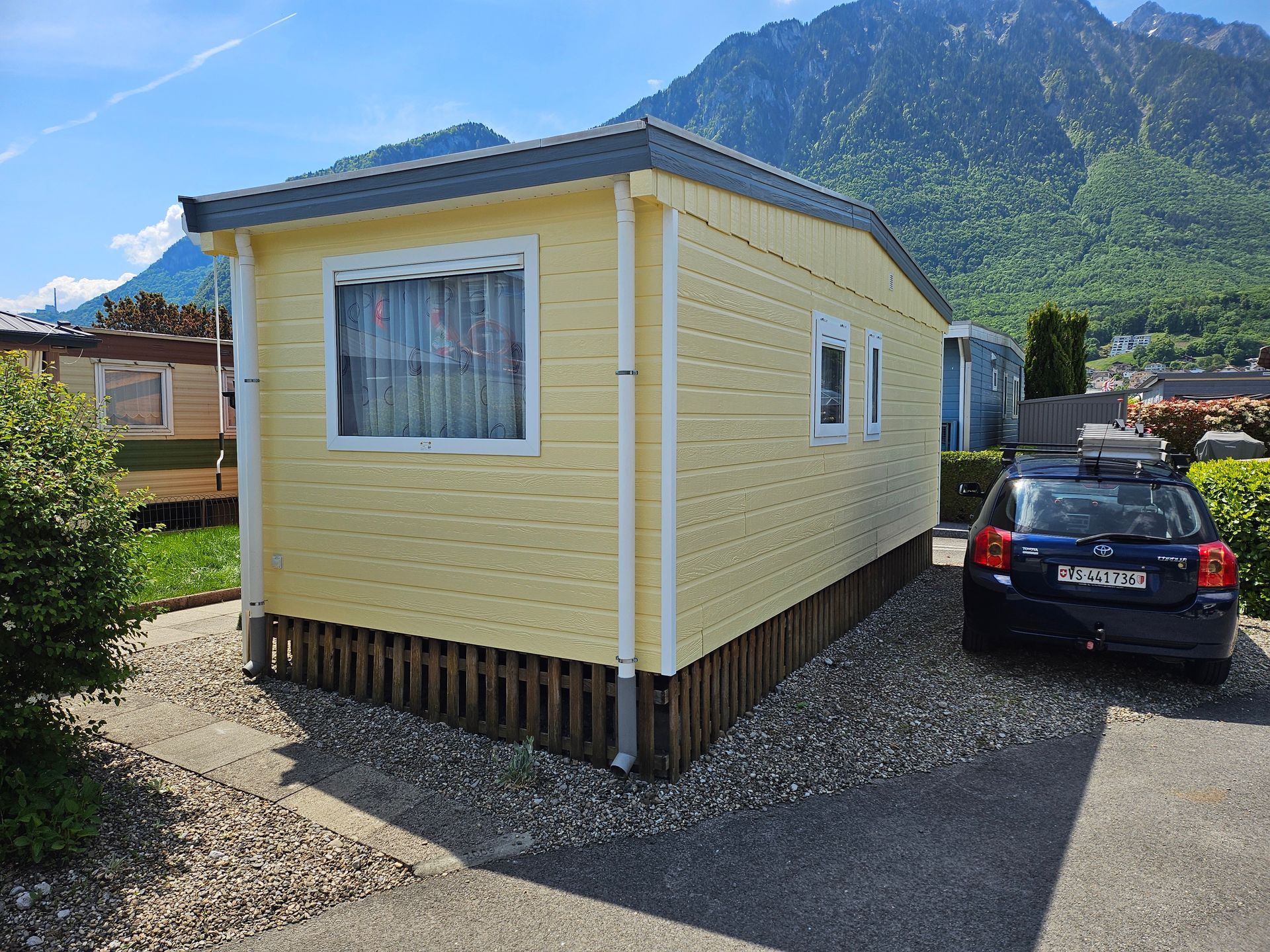 Avant et après la rénovation de l'extérieur d'une maison en bois : peinture brun clair à brun foncé ; ajout de volets rouges.