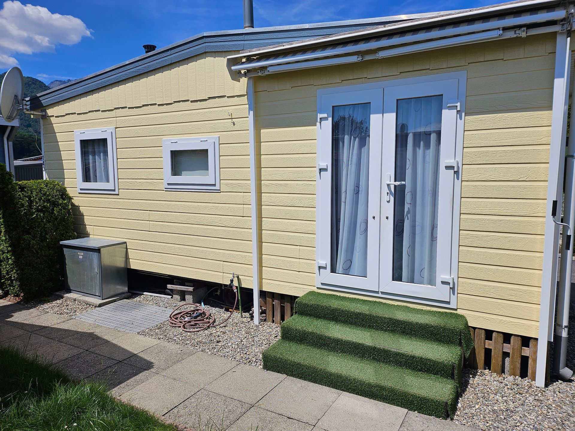 Maison en construction avec échafaudages. Façade en stuc blanc, réparations de toiture en cours et échelle.