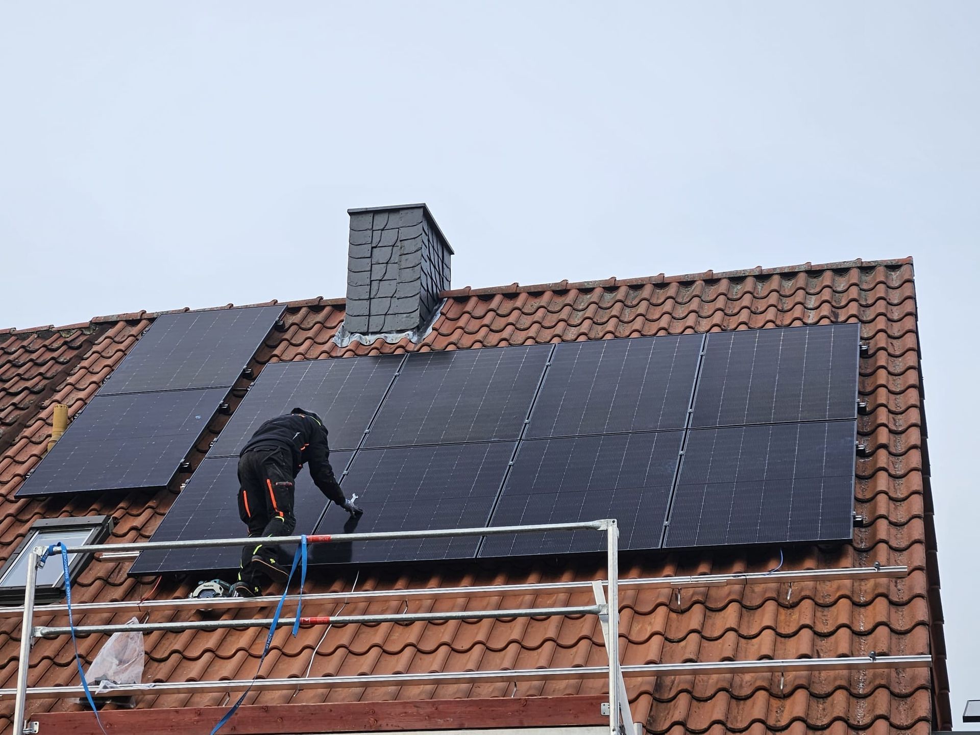 Ein Mann installiert Sonnenkollektoren auf dem Dach eines Hauses